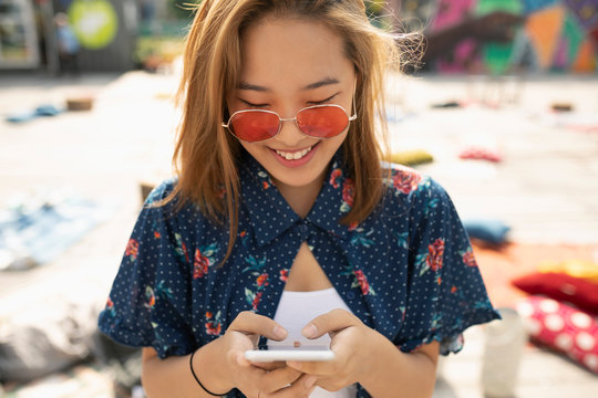 Teenage girl with sunglasses using smart phone