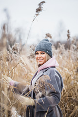 Portrait of a girl of European appearance on a winter walk, grass, forest, field, hat, health