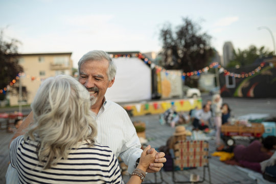 Affectionate senior couple dancing at movie in the park