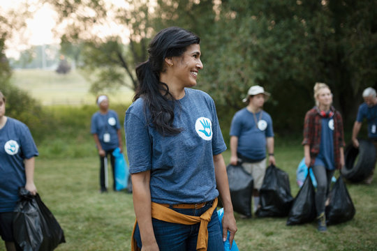 Smiling woman volunteering, cleaning up garbage in park