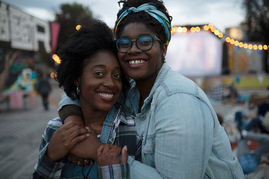 Portrait Smiling, Affectionate Sisters Hugging At Movie In The Park