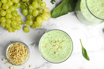 Flat lay composition with green buckwheat smoothie on white marble table
