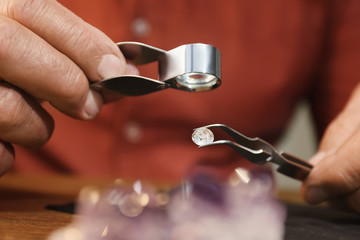 Professional jeweler evaluating beautiful gemstone, closeup view