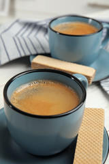 Delicious wafers and coffee for breakfast on table, closeup