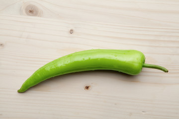 One red pepper on a wooden background.