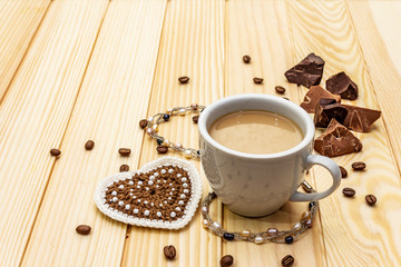 Valentine's Day concept. Cup of coffee, chocolate, knitted heart, string of pearl beads. Romantic breakfast and gift on wooden boards background, copy space