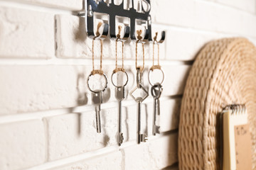 Metal key holder on white brick wall indoors, closeup