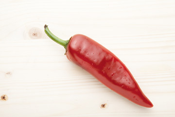 One red pepper on a wooden background.