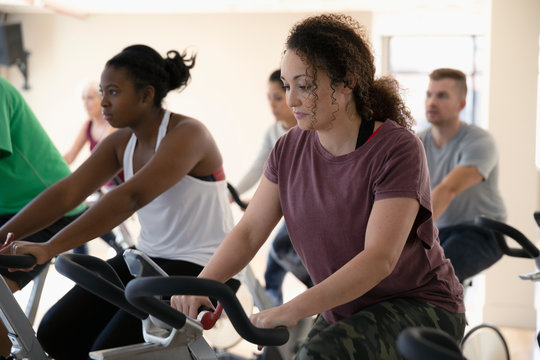 Focused Woman Riding Exercise Bike In Spin Class In Gym