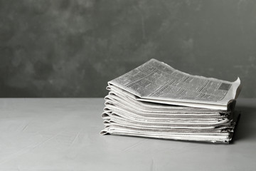 Stack of newspapers on light grey stone table, space for text. Journalist's work