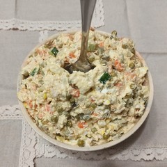 Bowl with Russian salad and spoon on table