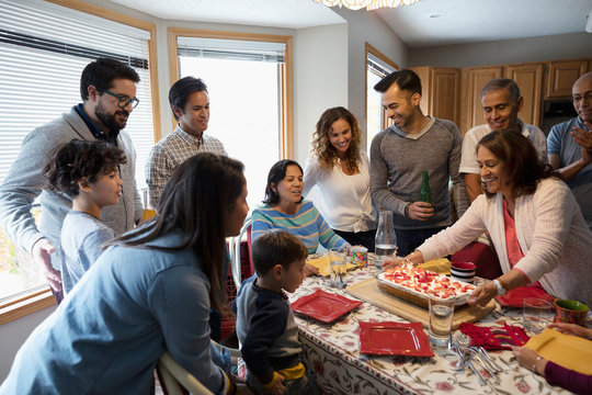 Latinx multi-generation family celebrating birthday with cake at kitchen table