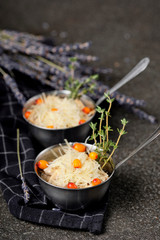 Festive french julienne with sea buckthorn in a bowl on napkin with bunch lavender on stone background. Rustic style. Baked mushroom julienne with chicken and cheese in pots. Top view. Close up