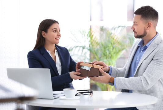 Man giving bribe to woman at table in office