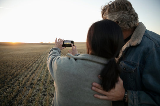 Farmer couple using camera phone in field