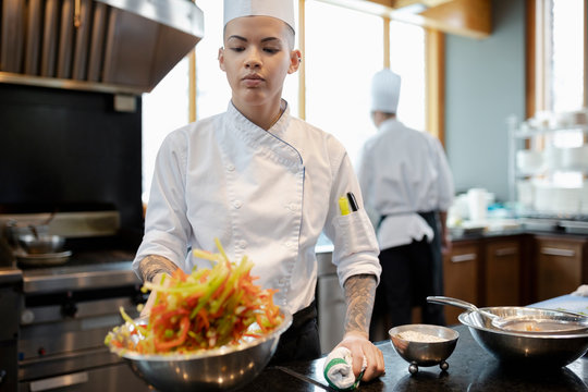 Female chef tossing vegetables in restaurant kitchen