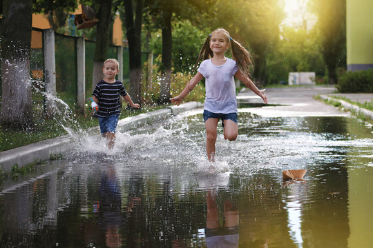 Cute happy kids jumping in the puddles