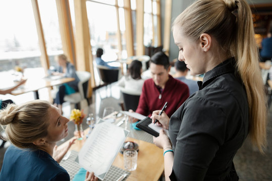 Waitress Taking Order From Couple At Restaurant Table