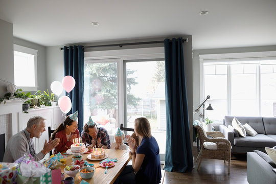 Multi-generation family celebrating toddler daughter s birthday at dining table