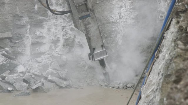 Excavator with big hydraulic rock breaker crushing limestone