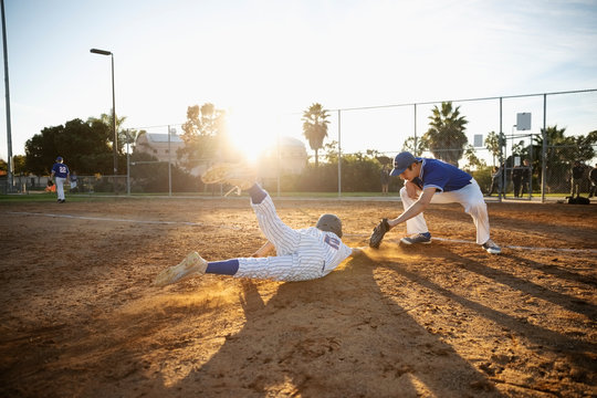 Baseball Player Sliding Into First Base On Sunny Field