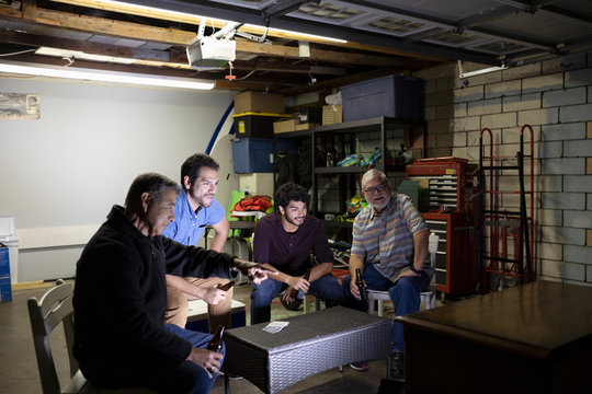 Latinx Men Watching Sports On TV In Garage