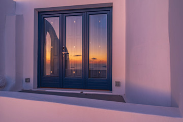 Fototapeta premium Tramonto riflesso sulla vetrata, isola di Santorini GR