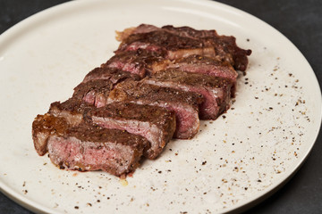 Grilled beef steak with spices on a white tray, close-up