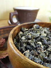 A scattering of green tea in a rustic dish and a Cup of tea