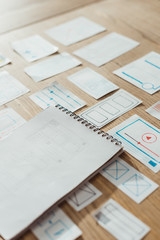 Fototapeta premium High angle view of notebook and user experience design sketches on wooden table