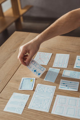 Cropped view of ux developer working with app sketches on table