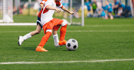 Boy Kicking Soccer Ball. Running Soccer Football Players. Five Junior Footballers on Duel. Football Grass Field and Soccer Stadium in the Background.