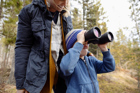 Mother and son with binoculars bird watching, hiking in woods
