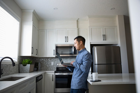 Man working from home, using laptop in kitchen