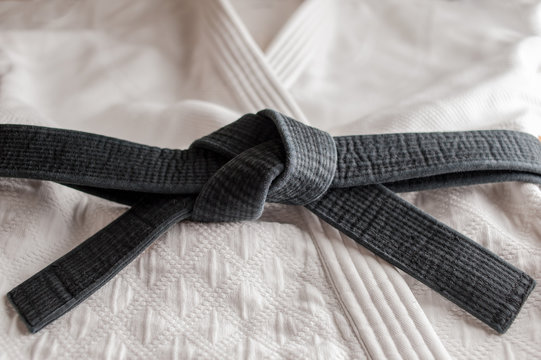 Black judo, aikido, or karate belt, tied in a knot, laying on martial art  uniform Stock Photo | Adobe Stock