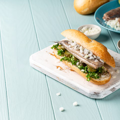 Traditional dutch snack, seafood sandwich with herring, onions and pickled cucumber. Broodje haring, copy space.