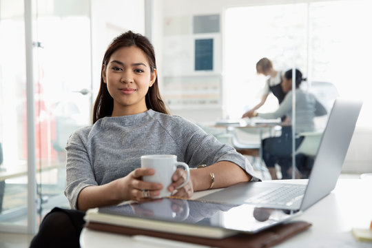 Portrait Confident Businesswoman Drinking Coffee At Laptop In Office