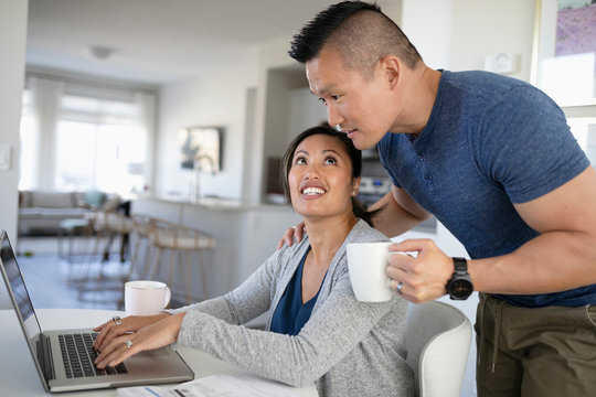 Couple paying bills and drinking coffee at laptop