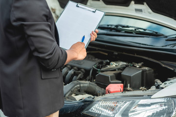 The mechanic is checking the engine and notes on a white paper.