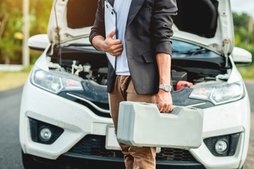 The auto mechanic is carrying the equipment to fix the car / and has a repair log.