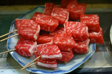 Freshly cut wagyu beef slices which were spiked on wooden sticks. Beef on a market in Osaka-Japan.