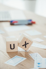 Selective focus of cubes with ux letters and website app layouts on wooden table