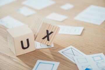 Selective focus of wooden cubes with ux letters and application layouts on table