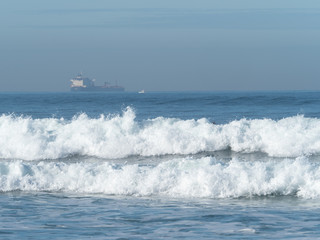 Waves breaking on Sopelana beach in Bilbao, with a merchant ship on the horizon.