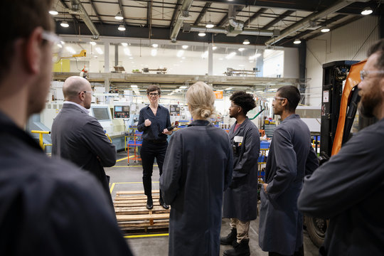 Female Supervisor Talking With Machinists In Factory