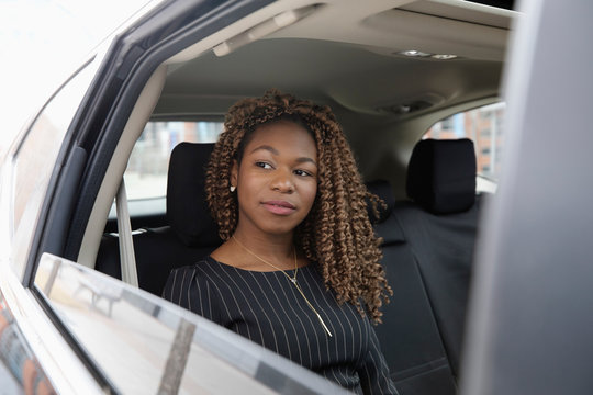 Thoughtful, ambitious businesswoman riding in back seat of crowdsourced taxi