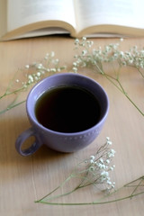 Cup of tea, book and gypsophila flowers on wooden table. Selective focus.