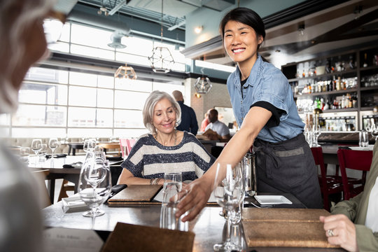 Friendly Waitress Serving Senior Women Friends In Restaurant