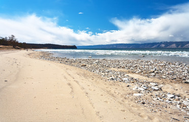 Lake Baikal in spring time. Sandy shore of Olkhon Island on the ice drift in the Small Sea Strait. Spring landscape, natural seasonal background