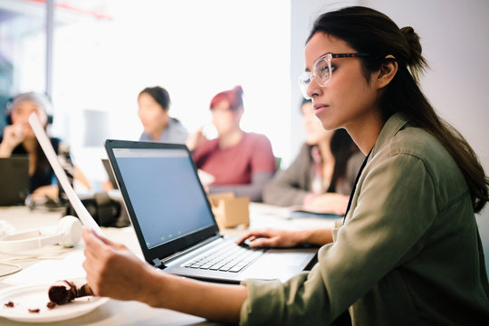 Focused Female Computer Programmer Coding At Laptop In Office